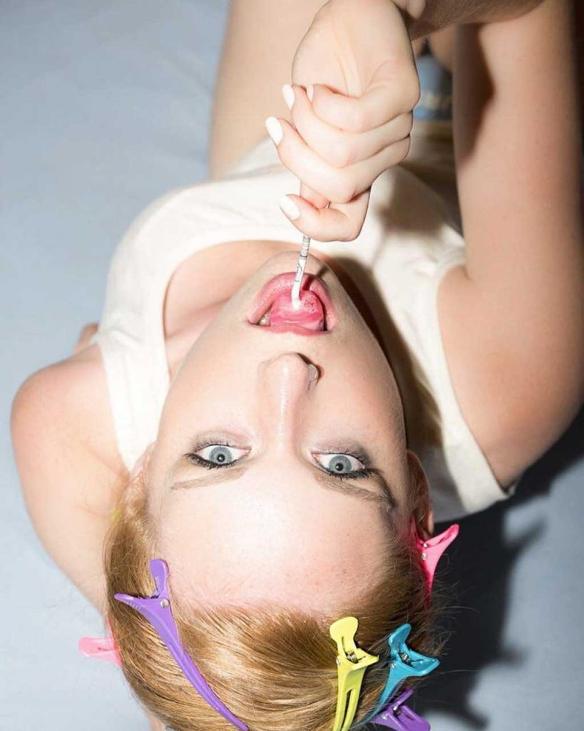 A girl licks candy on a stick