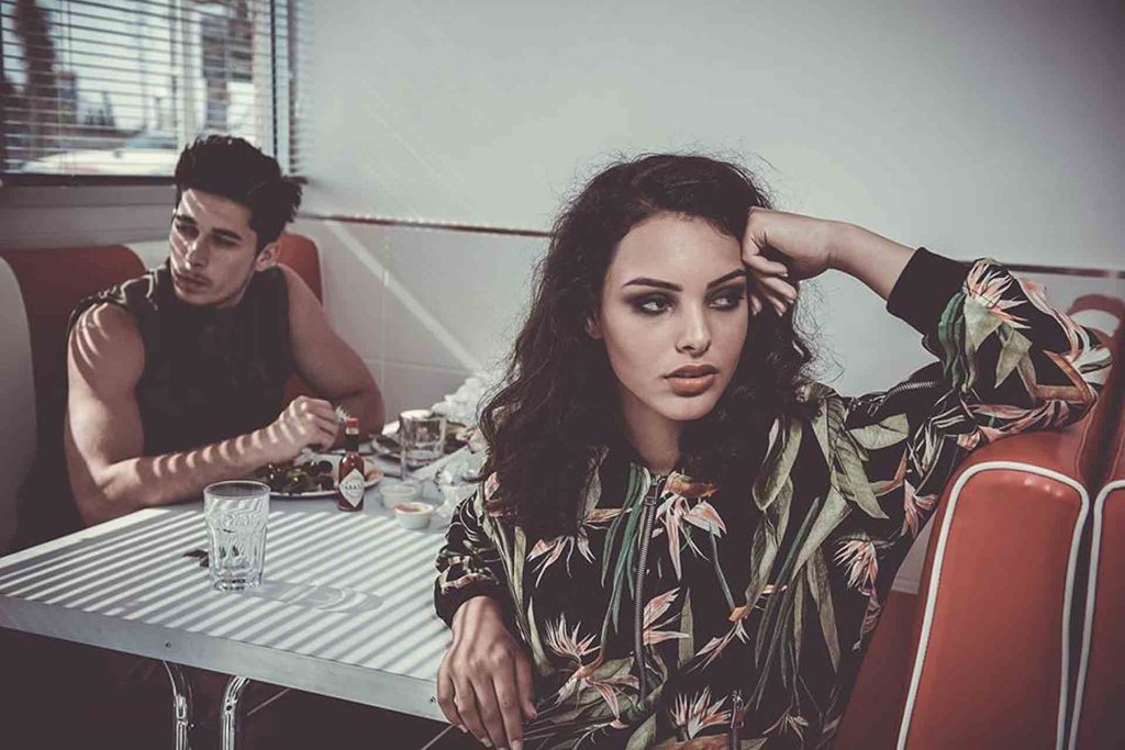 Models in fashion production sit in a restaurant
